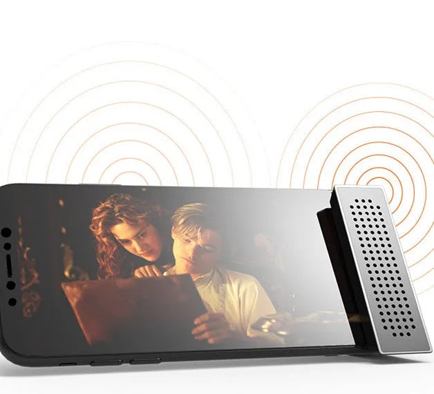 Portable black ABS plastic phone amplifier holder with an iPhone inserted, shown on a desktop.