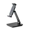 Folding aluminium and black plastic phone tablet stand on a desk, showing 360 degree rotation base.