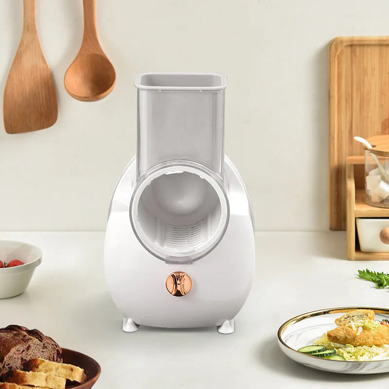 White electric vegetable slicer with rotary blades, suction base, and feeding port on a kitchen counter.