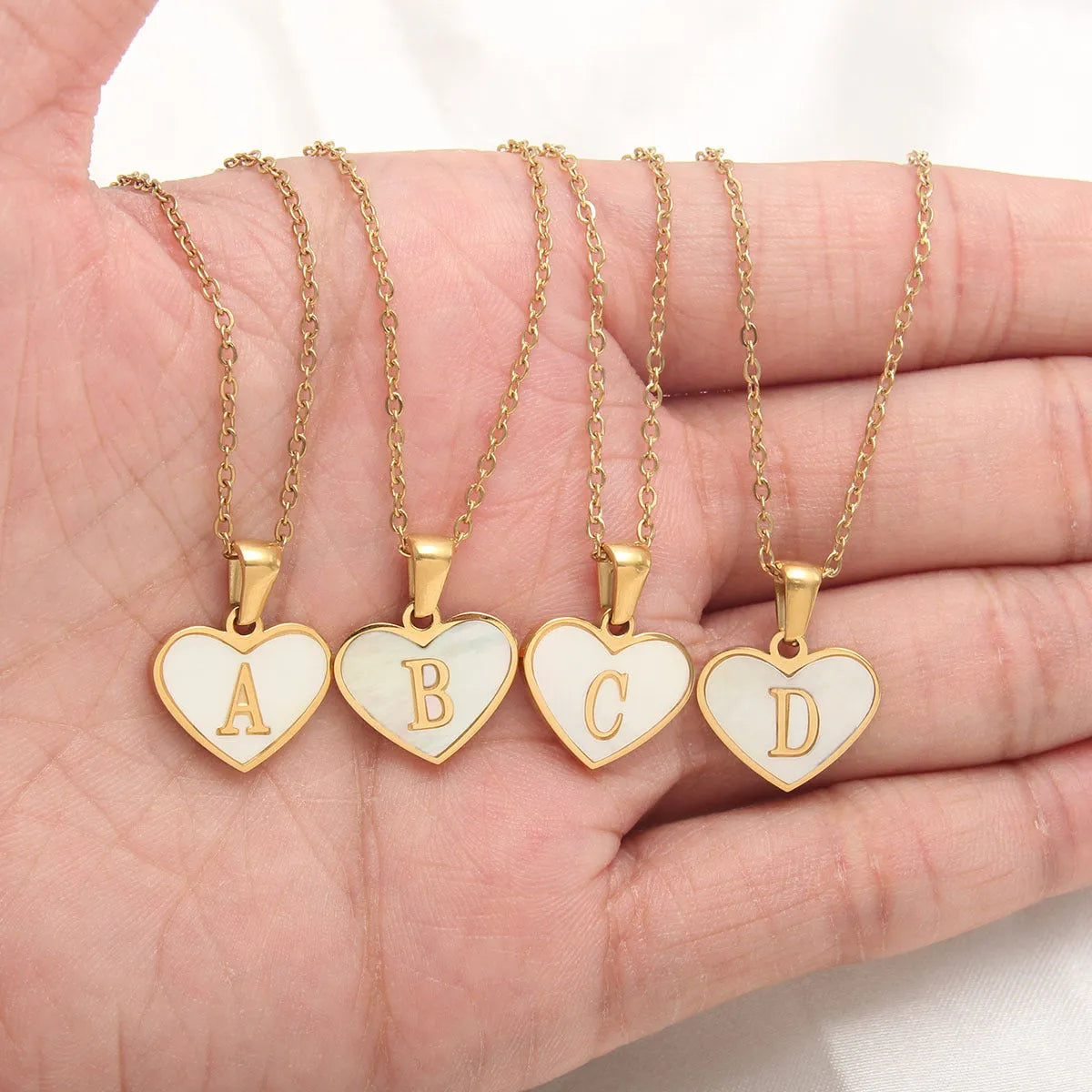 Gold heart-shaped white shell necklace with personalised letter charm on adjustable chain