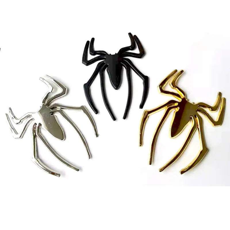 Three-dimensional metal spider bumper sticker in metallic finish on a car bumper.