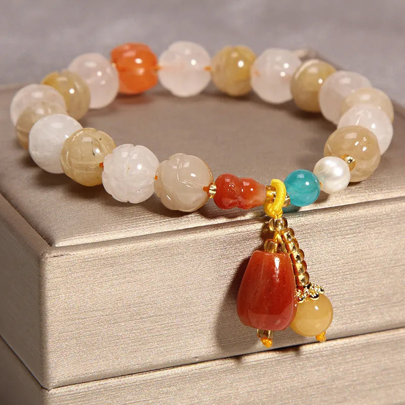 Close-up of a khaki yellow agate crystal bracelet with gold silk threading on a wrist.