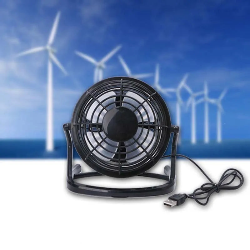 Mini adjustable USB desk fan in black on a desk next to a laptop