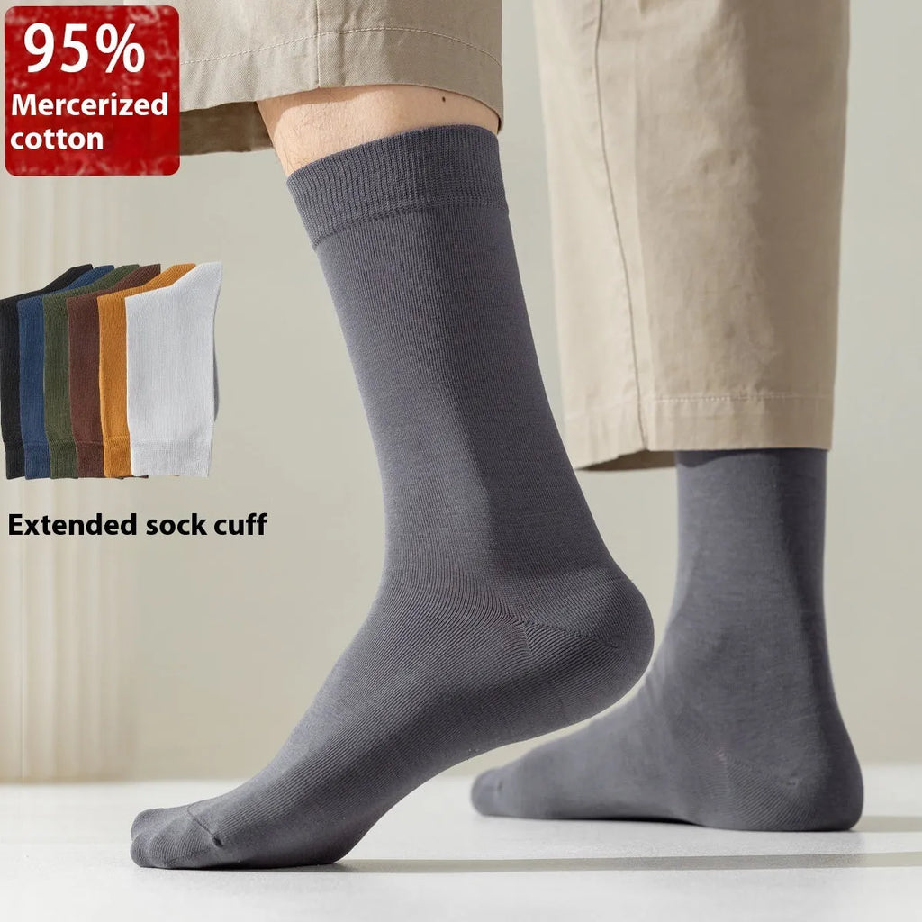 Pack of men's solid colour mid-calf business socks in combed cotton on a neutral background.