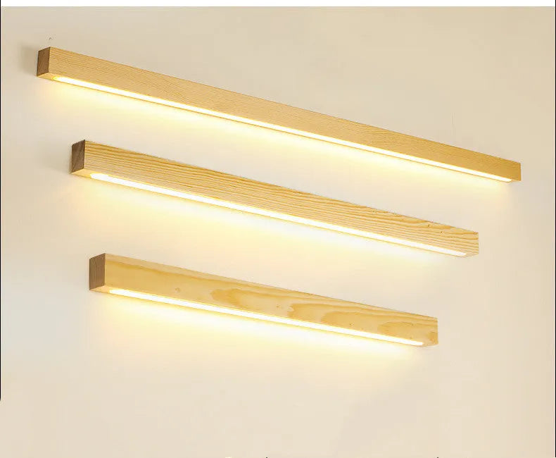 Slim walnut-colour wood and acrylic LED strip wall lamp in three length options on a white wall.