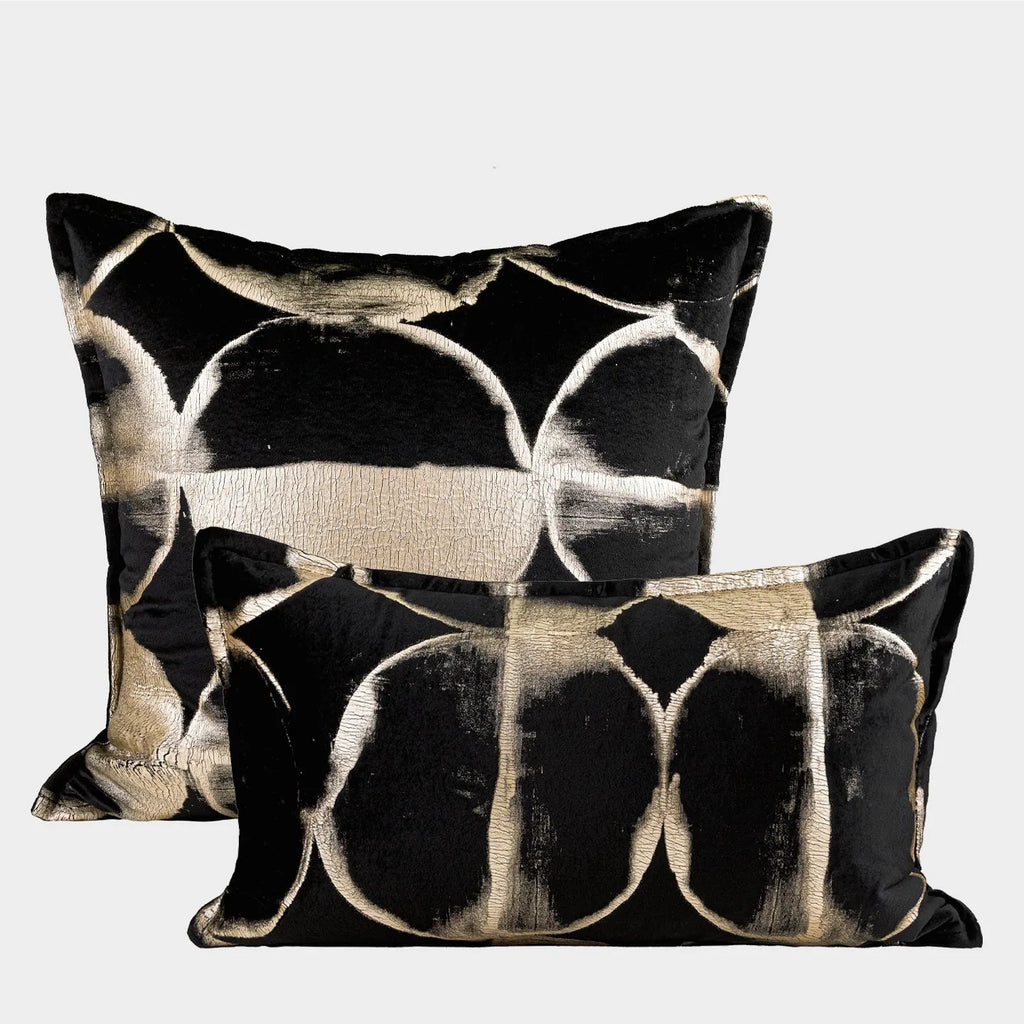 Black gold abstract patterned flannel decorative cushion on a sofa.