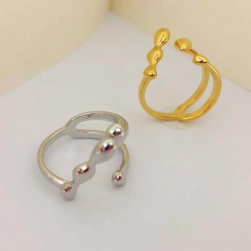 Brass opening ring with spherical element in gold colour on a hand.