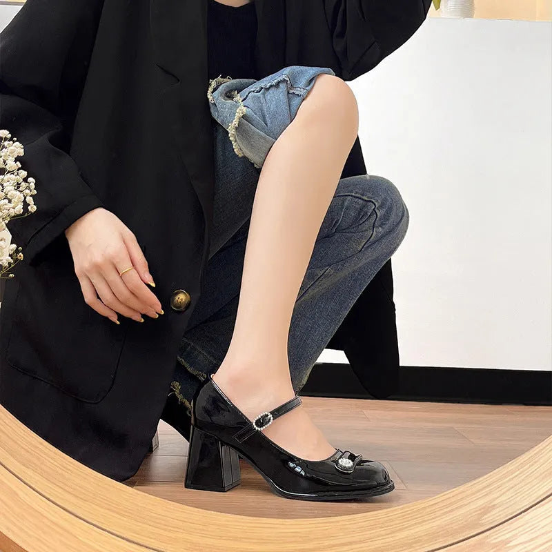 Women's black patent leather chunky heel shoes with round toe and buckle fastening on a white background.