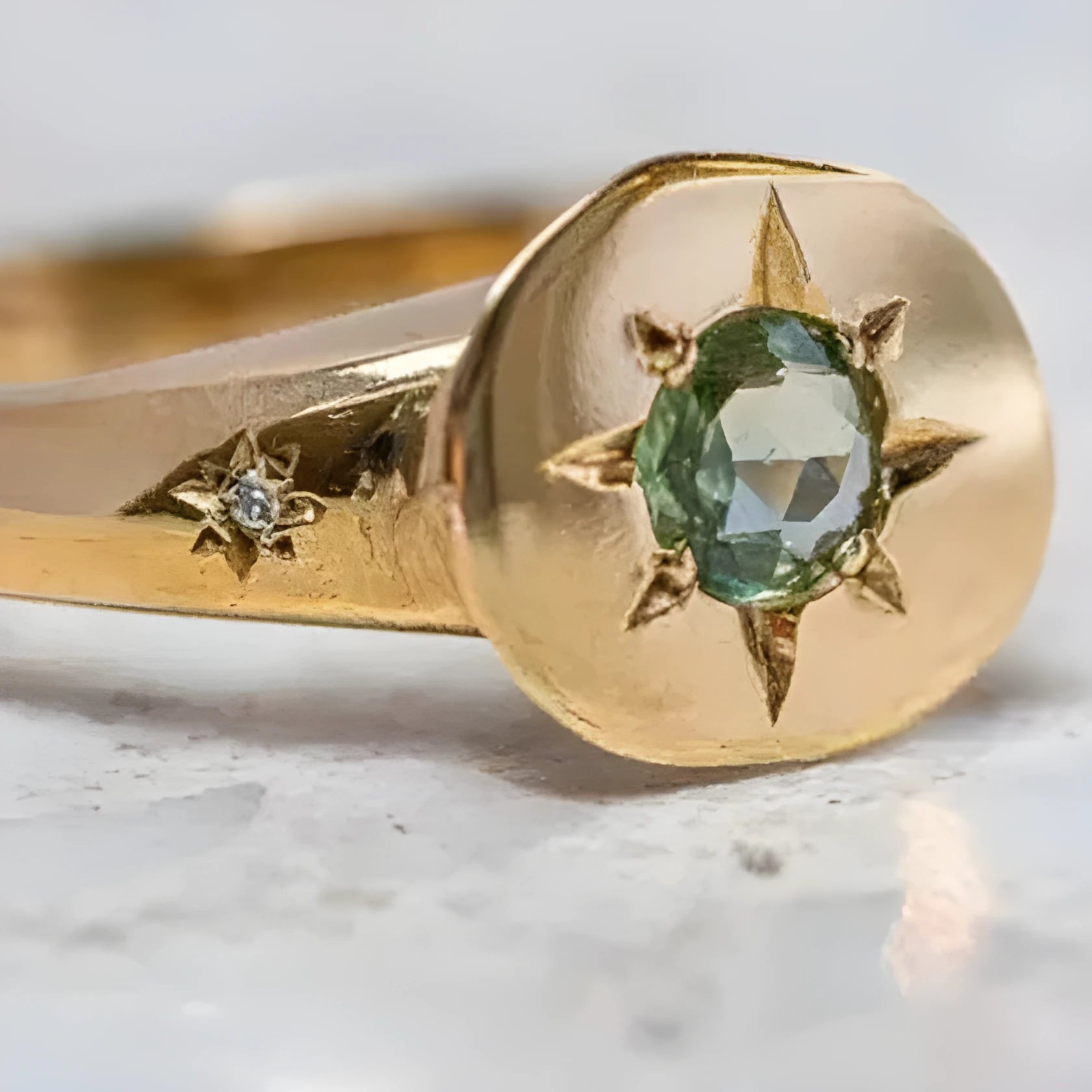 Gold coloured oval star zircon ring with adjustable opening on a plain background.
