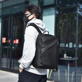 Large simple design waterproof backpack in grey with visible stitching, shown with a separate computer bag.
