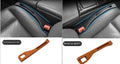 Black plastic car seat gap storage box with handle inserted between vehicle front seats.