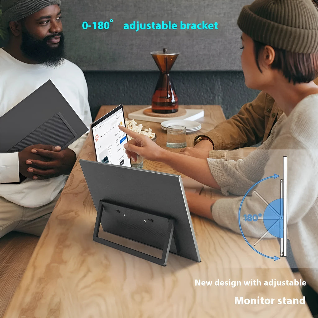Black 15.6-inch portable LED monitor with adjustable stand on a desk next to a laptop.
