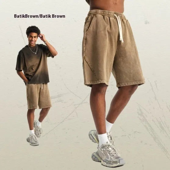 Man wearing batik-washed black cotton shorts with a loose fit and a retro patch on the leg.