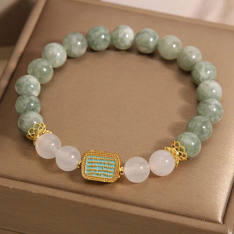 Natural crystal bracelet for women oil green emerald colour with sutra carvings on a white background