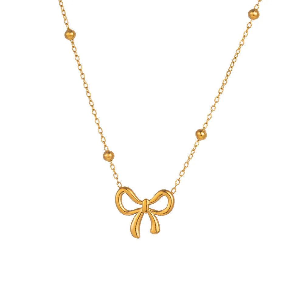 Gold-coloured titanium steel bow necklace with cross chain detail on white background