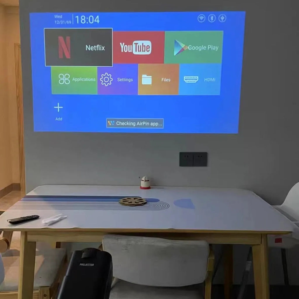 A white home projector unit on a wooden surface, showcasing its lens and wireless capabilities for HD projection.