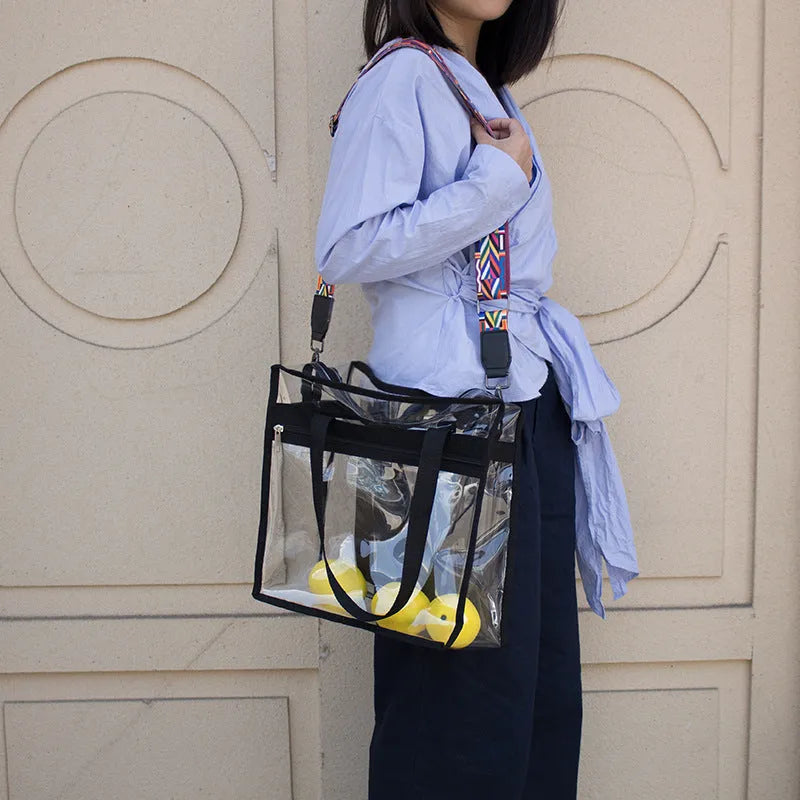 Women's transparent PVC shoulder messenger bag showing front organisation and double strap connector