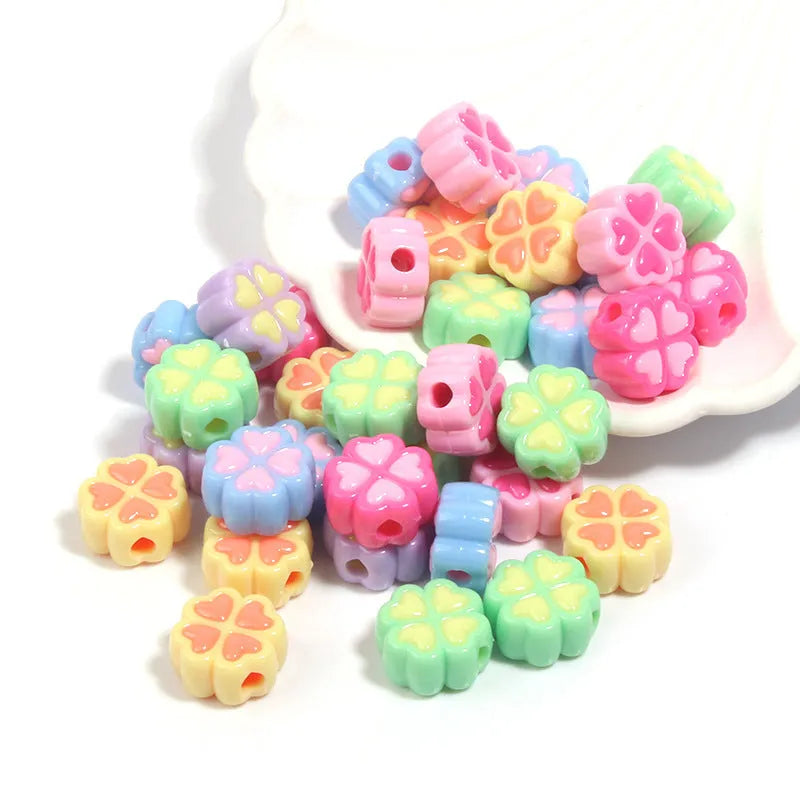 Assortment of 15mm frosted acrylic four-leaf clover craft beads in light colours.