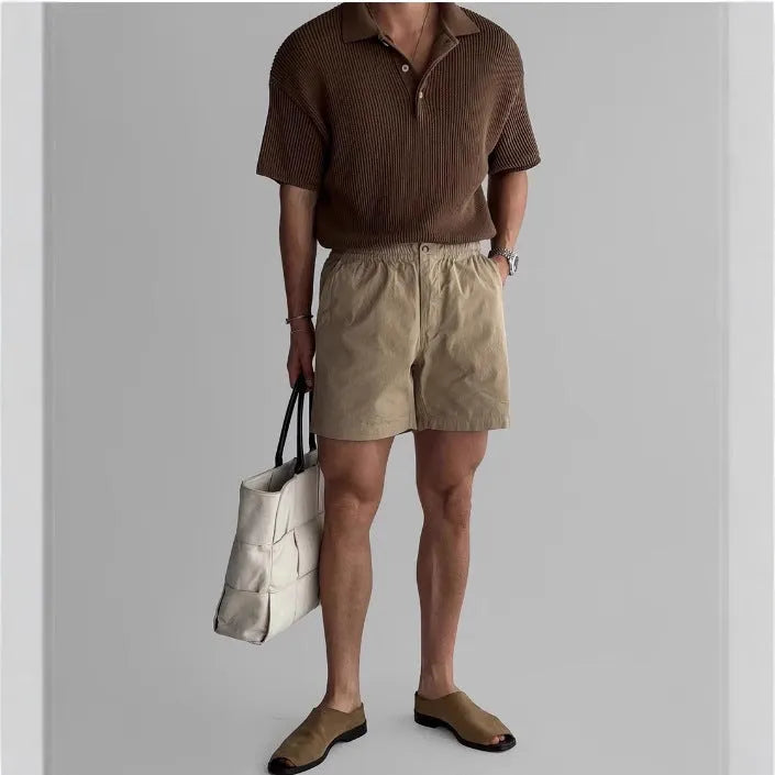 Men's loose-fit cotton sports shorts in black, shown on a hanger against a white background.