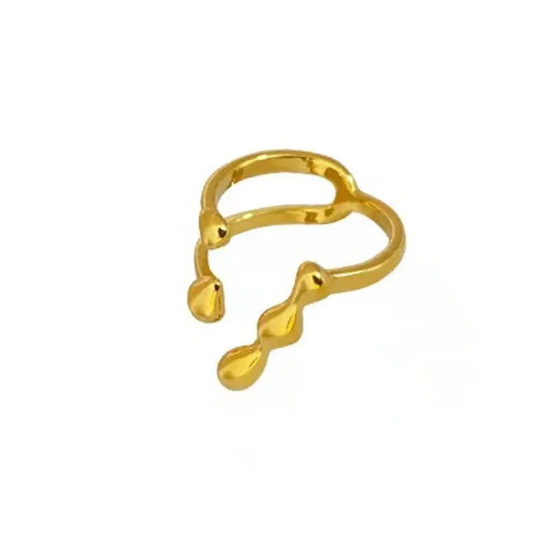 Brass opening ring with spherical element in gold colour on a hand.
