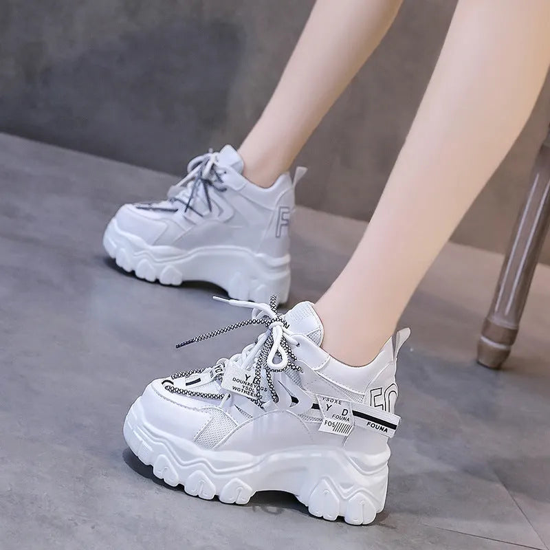 White and black women's low-top platform sports shoes with cross-strap and mesh design on a rubber sole.