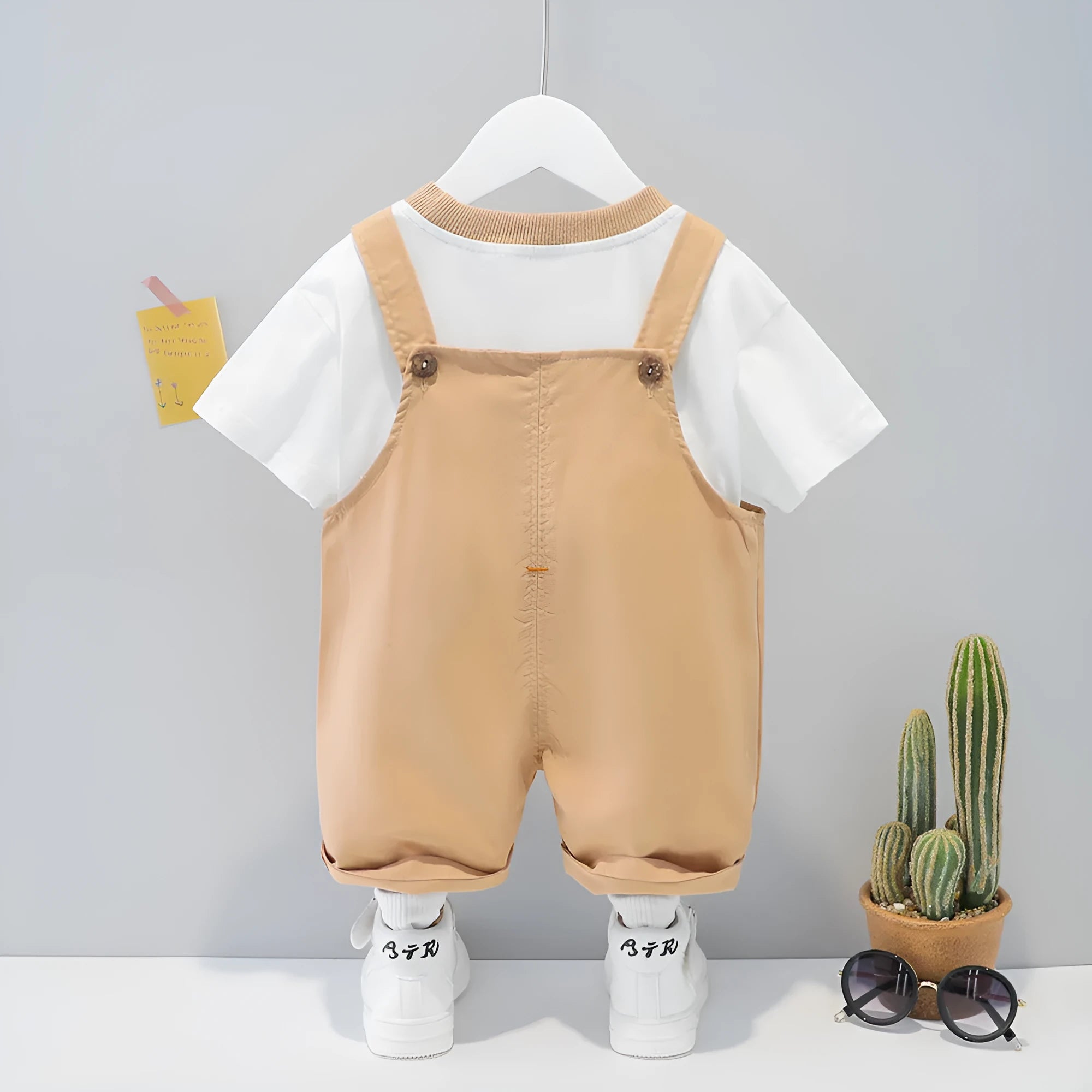 Baby wearing yellow cotton summer overalls with cartoon design, short sleeves, and adjustable straps