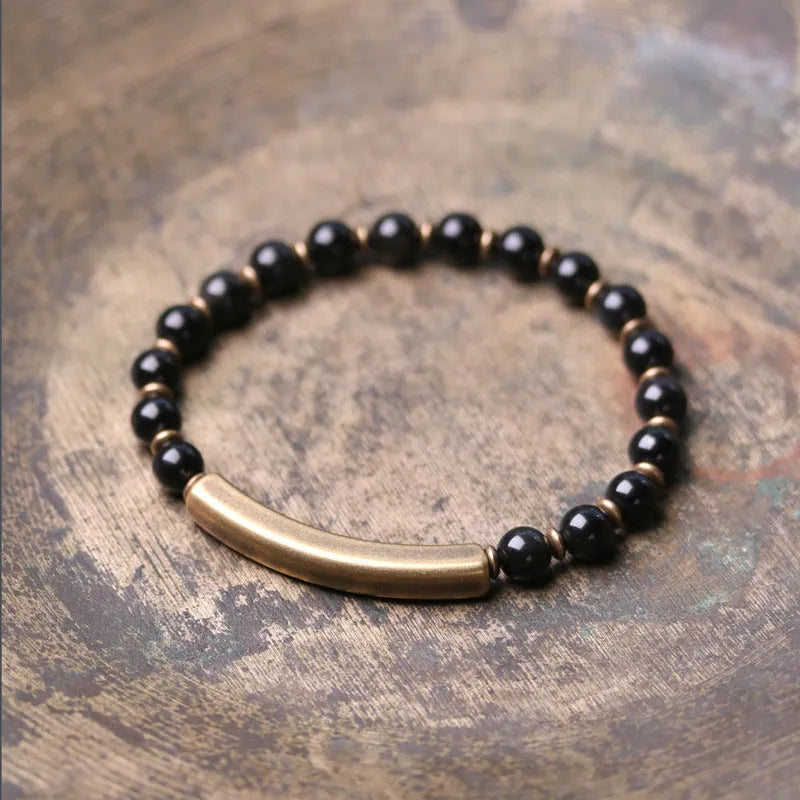 Layered retro ethnic bracelet with water plants agate, obsidian, and red stone beads and brass accents on a neutral background.
