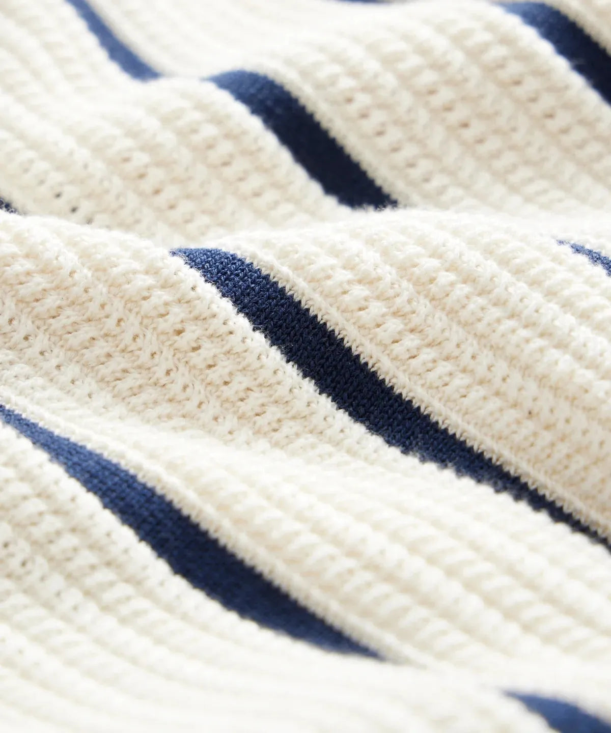 Man modelling a white short sleeve knitted top with asymmetric stripes and a lapel collar.