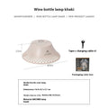 Beige wine bottle shaped camping lantern with USB-C port, shown lit on a wooden table outdoors.