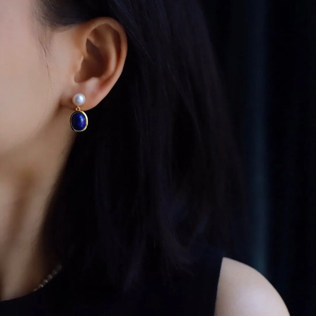 A pair of simple 925 silver earrings with a blue lapis lazuli pearl and auspicious pattern details.