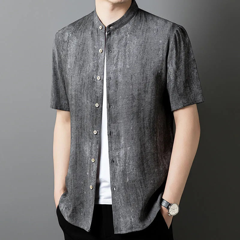 A man wearing a loose-fitting, short-sleeved casual shirt with a stand collar in a grey colour.