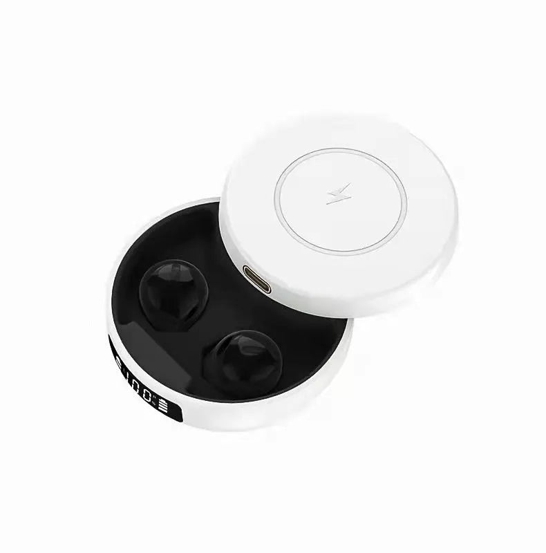 Mini black wireless semi-in-ear headphones sitting in their open white charging case on a table.