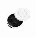 Mini black wireless semi-in-ear headphones sitting in their open white charging case on a table.