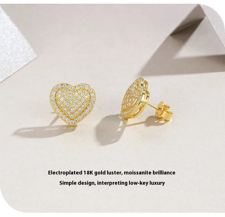 A pair of simple S925 sterling silver stud earrings with a gold-coloured finish and a heart-shaped moissanite stone.