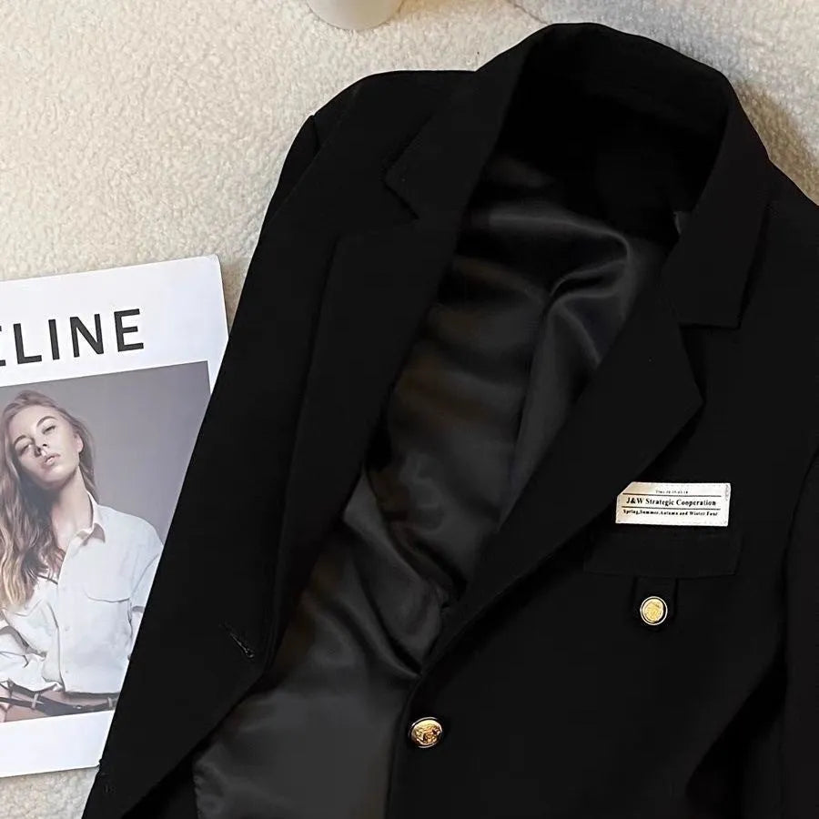 Black women's loose-fit short suit coat with long sleeves and a pocket.