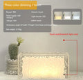 Small modern geometric acrylic night lamp with coloured LED light on a wooden surface.