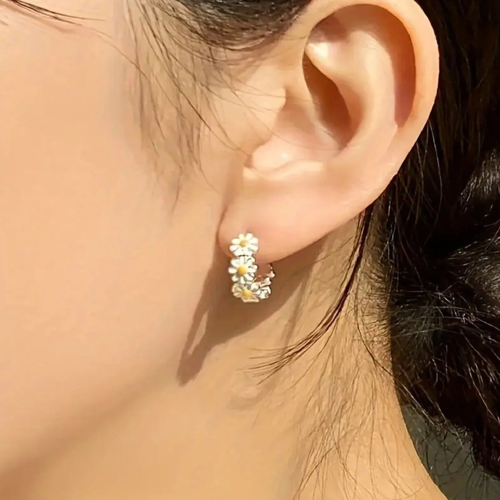 A pair of white daisy flower ring earrings with platinum inlaid gemstones on a copper base.