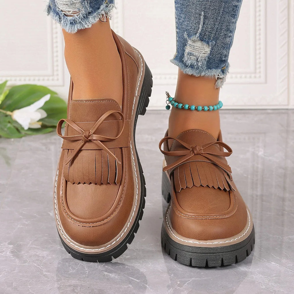 Black plus size women's loafer with tassel decoration and a bowknot on a low chunky heel.