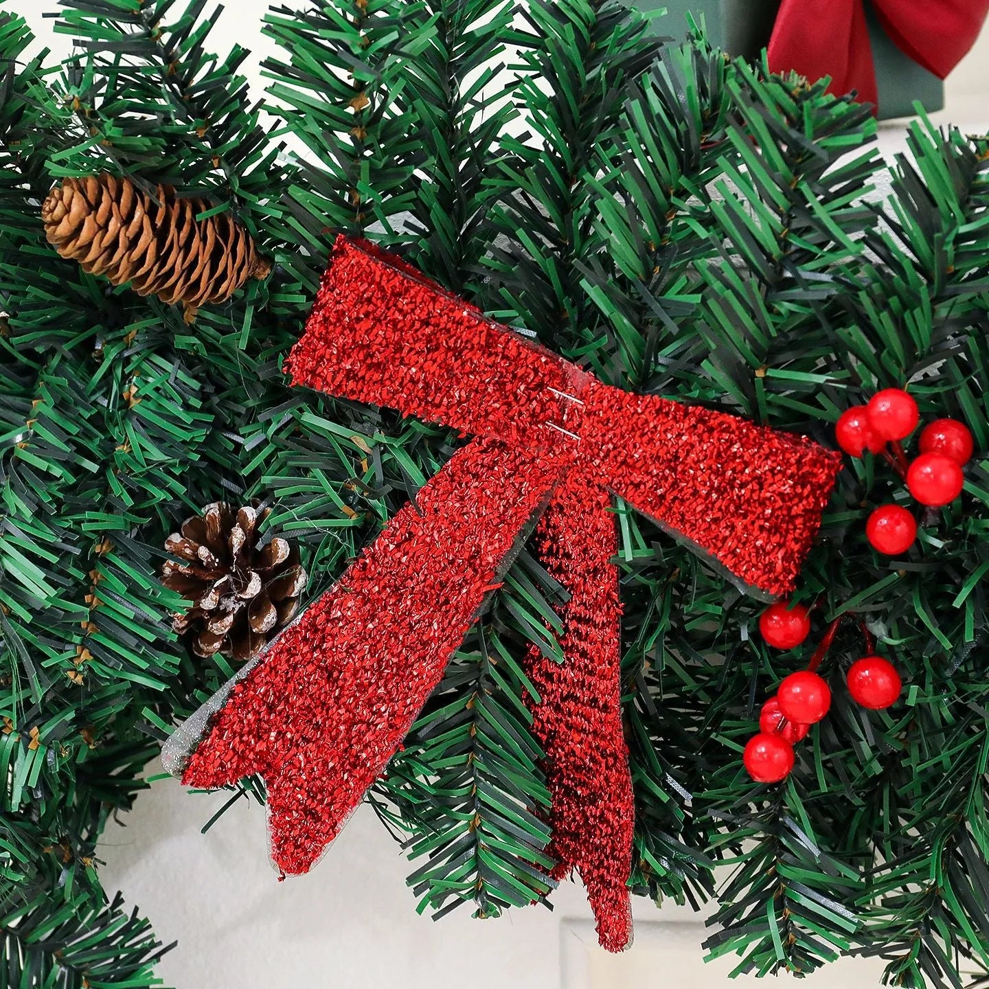 Christmas rattan wreath decoration with pine cones and red bow on green background
