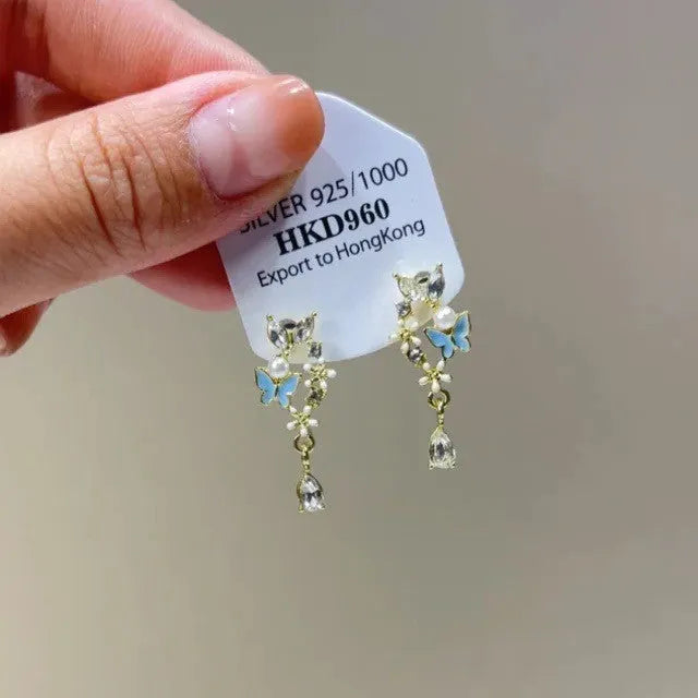 Geometric alloy ear clip with a heart rhinestone and dangling tassel, showing both stud and clip-on back options.