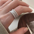 Geometric copper alloy ring with woven twisted design and adjustable opening.