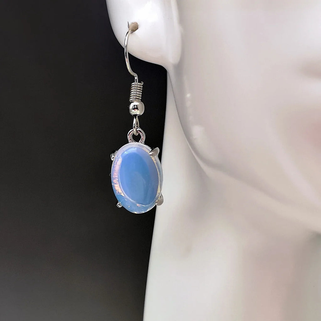 A pair of retro opal earrings with a moonstone eardrop and cross design in electroplated alloy.
