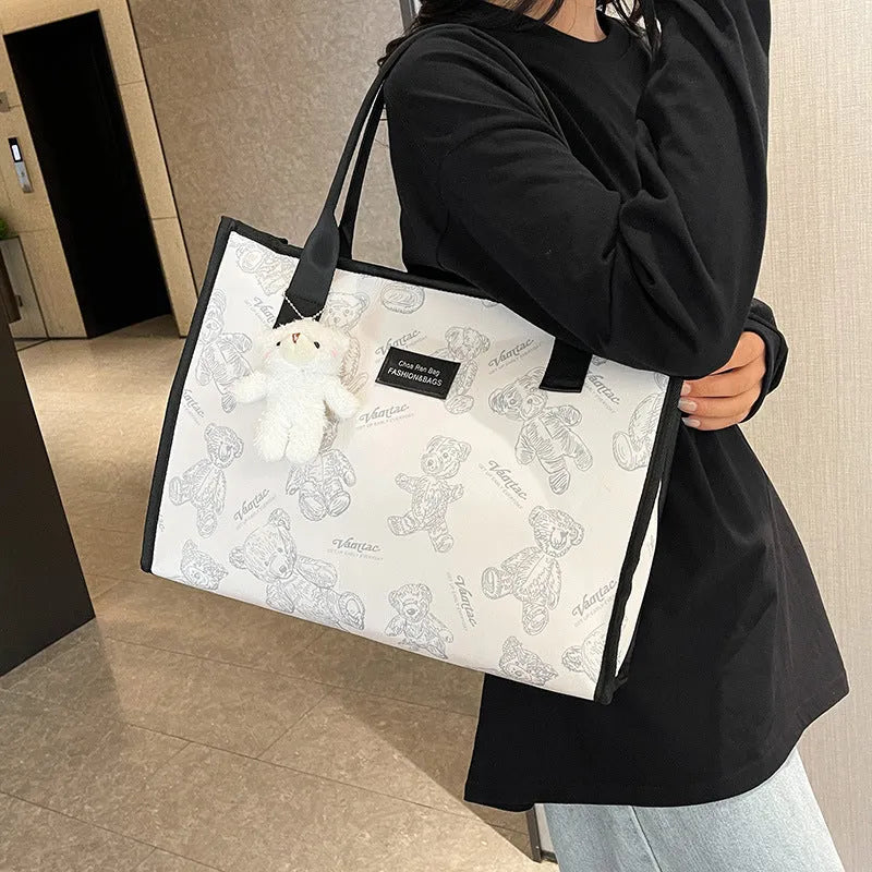 Women's black canvas tote bag with rhombus pattern showing horizontal square shape and shoulder strap