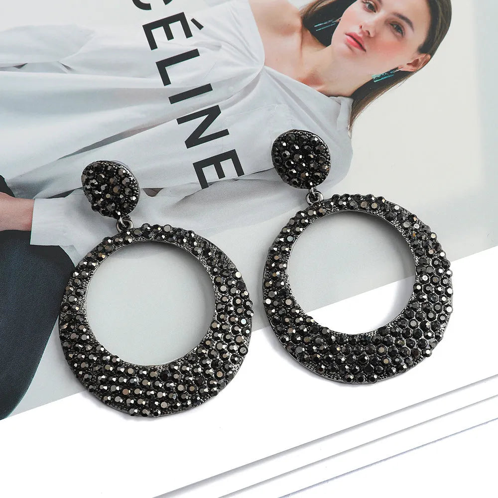 A pair of large round colourful alloy pendant earrings with a cartoon style on a white background.