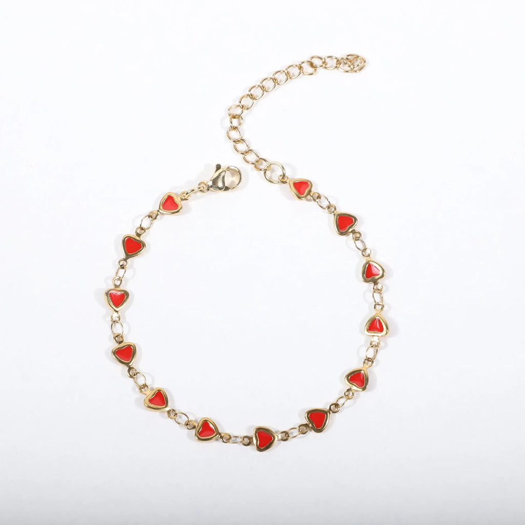 Stainless steel bracelet with heart charm in 18K gold plating, shown in adjustable length on a wrist.