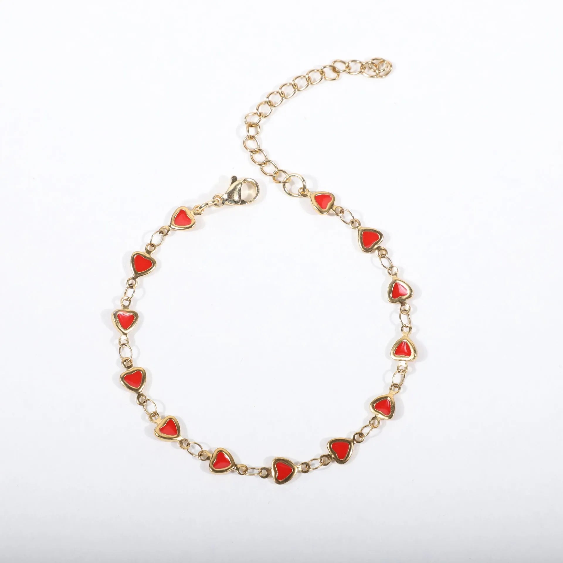 Stainless steel bracelet with heart charm in 18K gold plating, shown in adjustable length on a wrist.