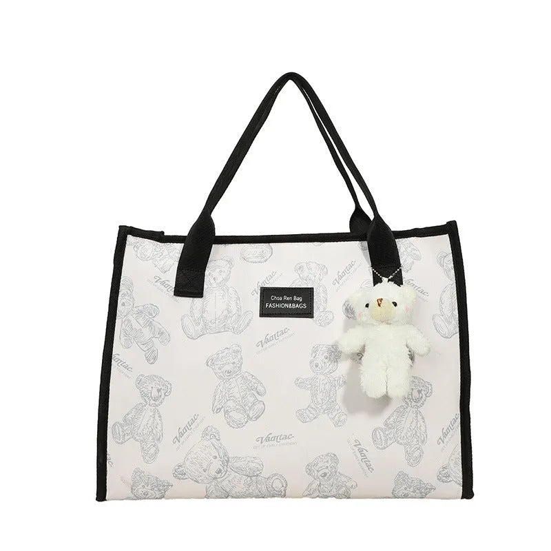 Women's black canvas tote bag with rhombus pattern showing horizontal square shape and shoulder strap