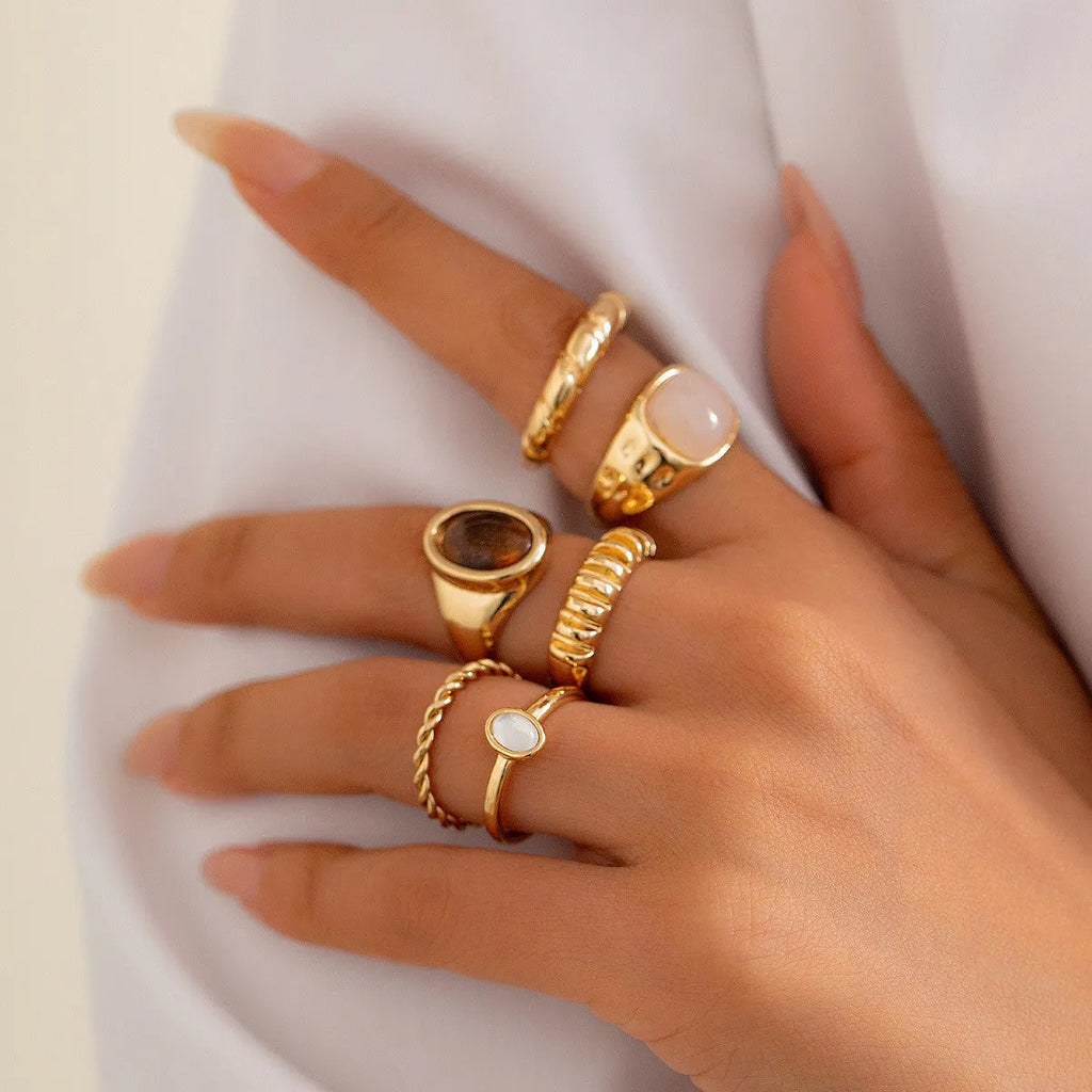 Six light gold alloy rings with irregular geometric shape, electroplated finish, on display