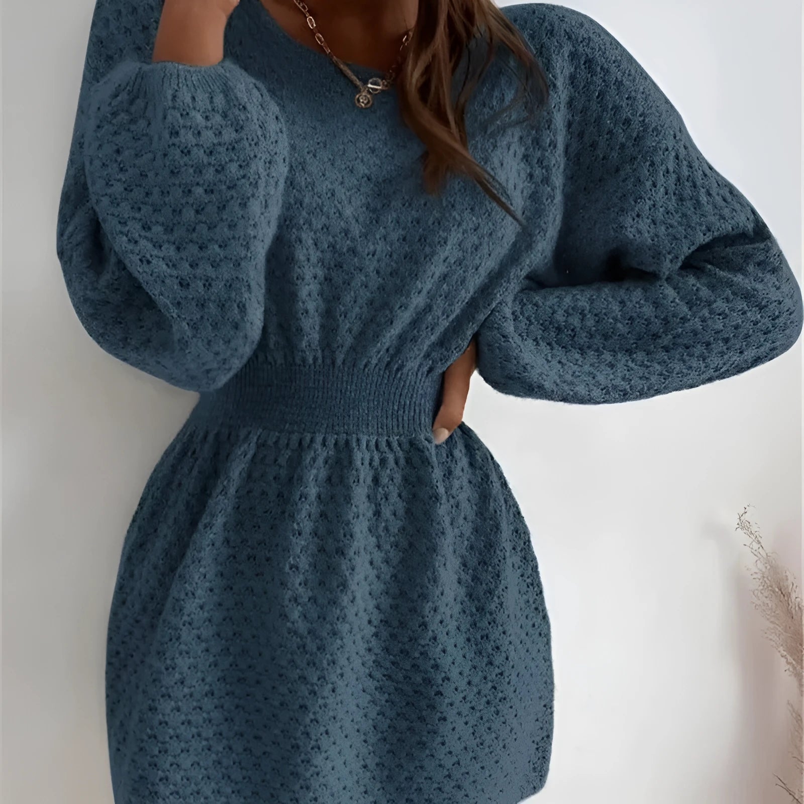 Blue women's knitted dress with French neckline, fitted waist, and hand-crocheted flower detailing