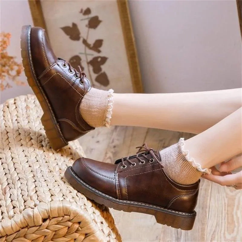 Women's black preppy style low-heel Mary Jane shoe with front lace-up and round toe on a white background.